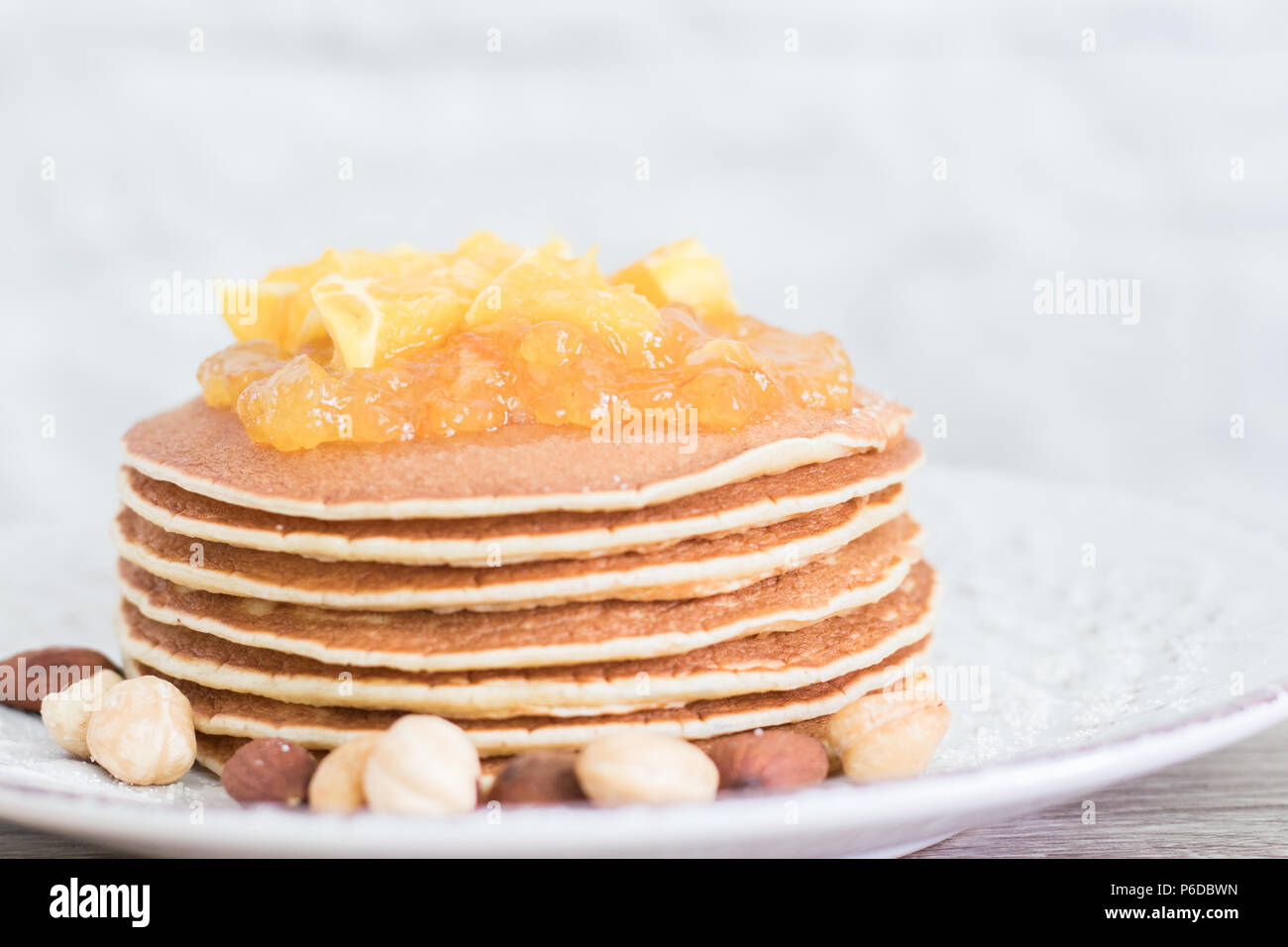 Pila di fresco frittelle supportato su una piastra vintage con dadi e orange jam sulla parte superiore. Vista frontale. Spazio di copia Foto Stock