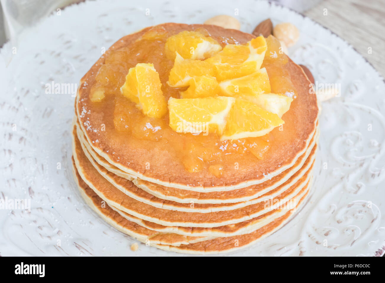 Pila di fresco frittelle supportato su una piastra vintage con orange marmellata e frutta a fette sulla parte superiore. Foto Stock