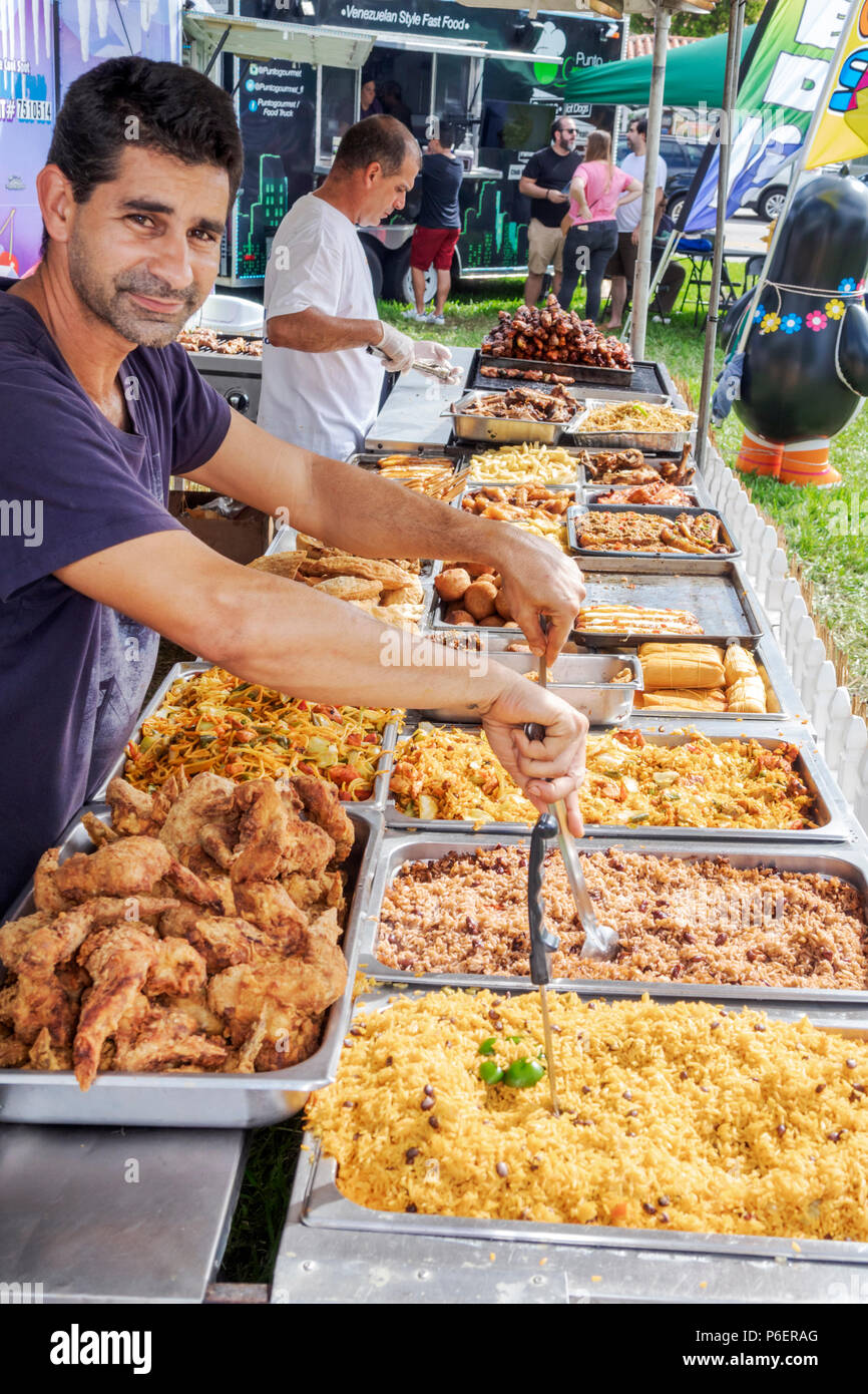 Florida,Coral Gables,Festival culturale ispanico,tenda stalla venditore di cibo latino-americano,vendita display,uomo ispanico maschio,vassoi alimentari,pollo fritto,riso Foto Stock