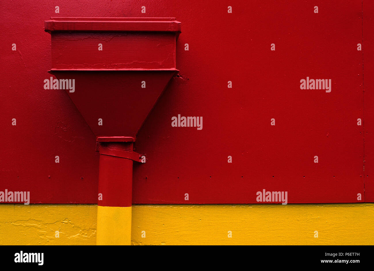 Lato di edificio con scarico grande dipinto di rosso e di giallo Foto Stock