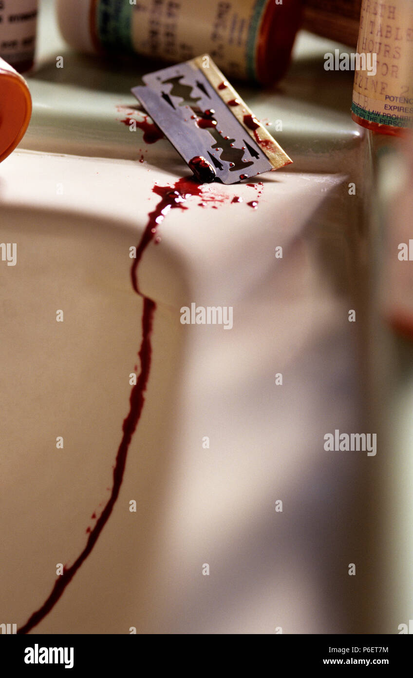 Close-up di una lama di rasoio sul lavandino del bagno di sangue di gocciolamento dopo il tentativo di suicidio. Foto Stock