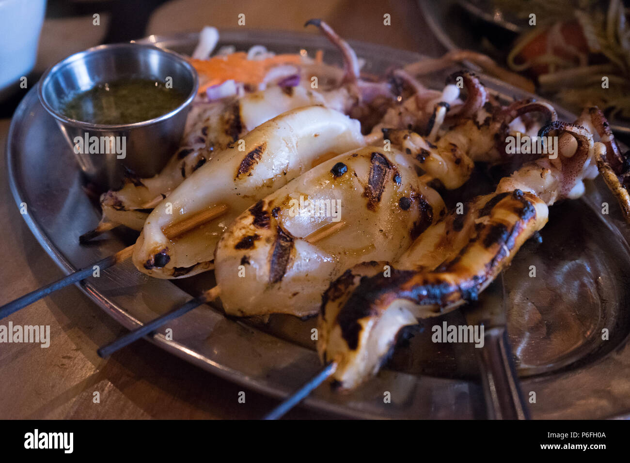 Calamari alla griglia sul bastone di bambù con salsa piccante piatto tailandese Foto Stock
