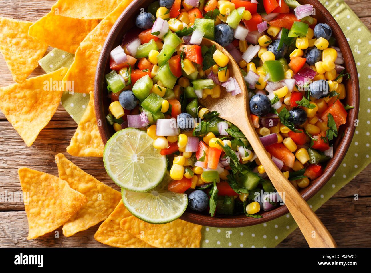 Salsa piccante da mais, mirtilli, peperoncino jalapeno, il peperone e la cipolla è servita con nachos vicino sul tavolo. parte superiore orizzontale vista da abov Foto Stock