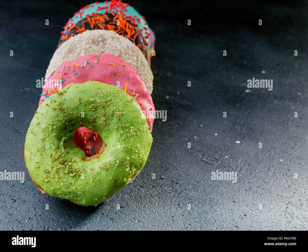 Le ciambelle con una glassa colorata su sfondo scuro Foto Stock