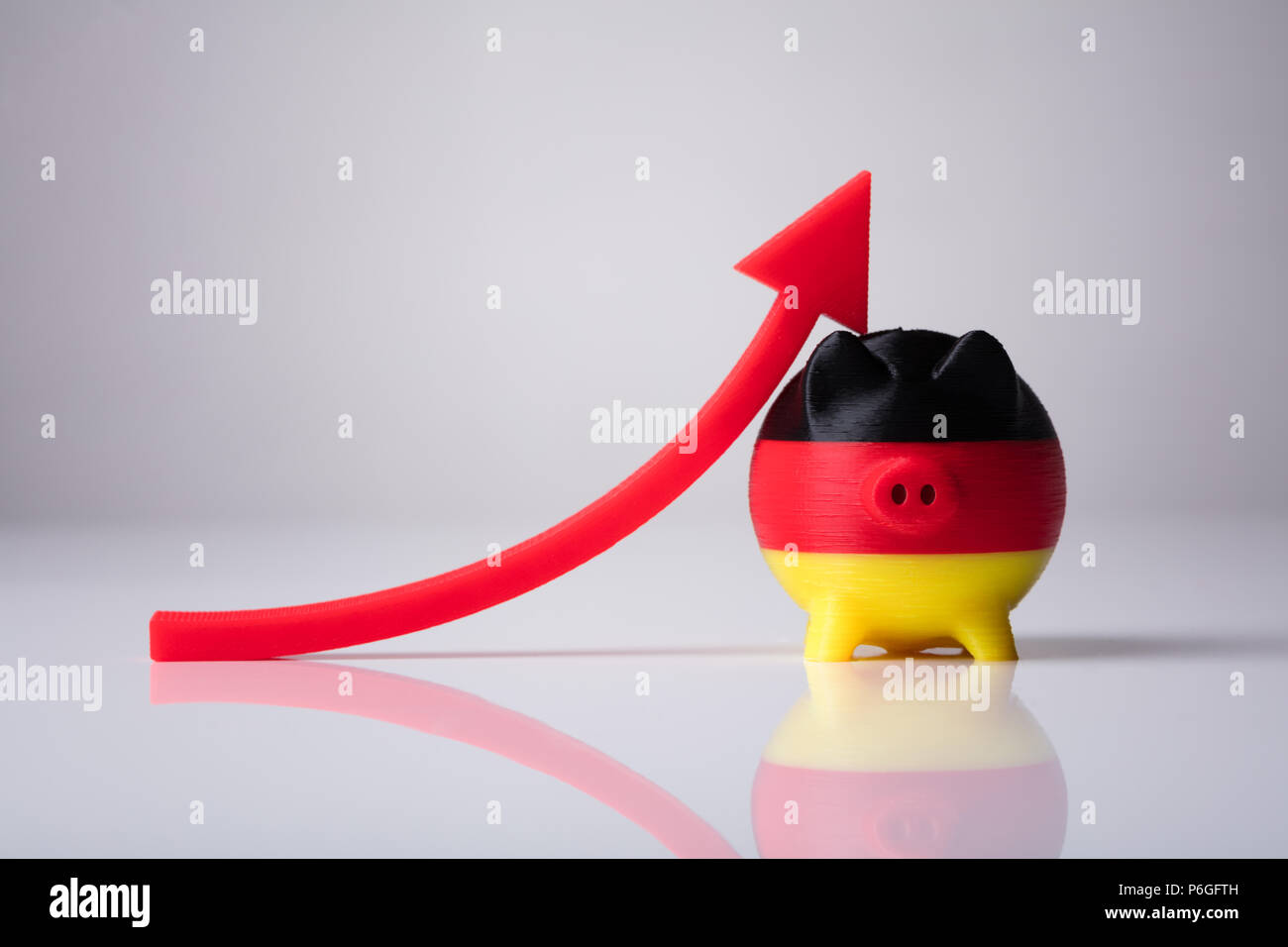 Close-up di Piggybank dipinta con bandiera tedesca e in rosso la freccia mostra la direzione verso l'alto Foto Stock