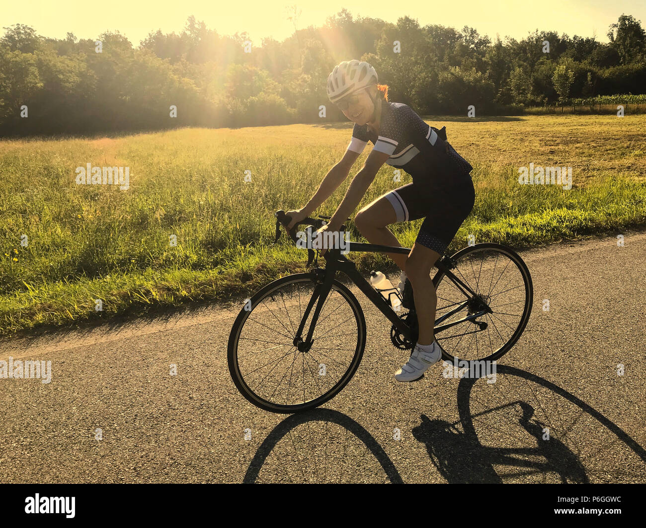 Donna ciclista ciclismo all alba di una donna ciclista pedalando in Italia Estate Meteo golden sun luce paesaggio di campagna Foto Stock