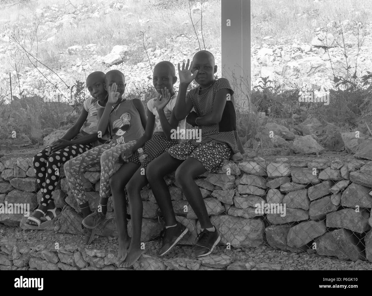 KHOHAXIS, NAMIBIA - 21 maggio 2018; gruppo di ragazze africane l'ombra sventolando felicemente risponde ad essere fotografati in bianco e nero Foto Stock