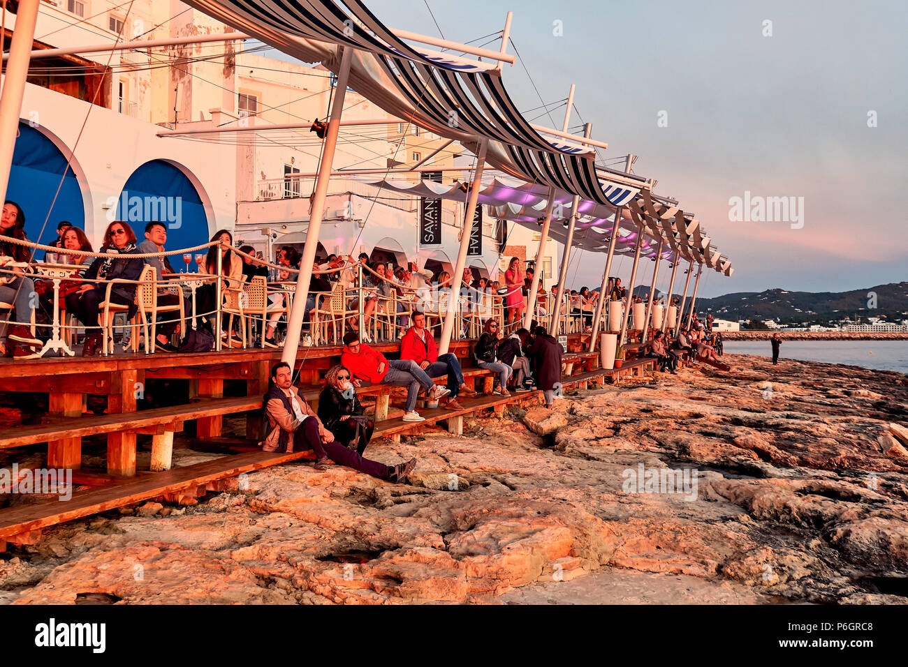 Isola di Ibiza, Spagna - 1 Maggio 2018: una folla di gente che soddisfano il tramonto dalla terrazza fronte mare di Cafe Del Mar. Questo luogo è famoso per le viste al sole Foto Stock