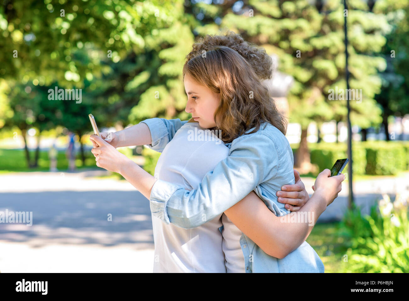 Il ragazzo con ragazza abbracci. In estate la natura. Nelle mani di trattenere gli smartphone. Per corrispondere alle reti sociali. Il concetto di fiducia è la felicità di tog Foto Stock