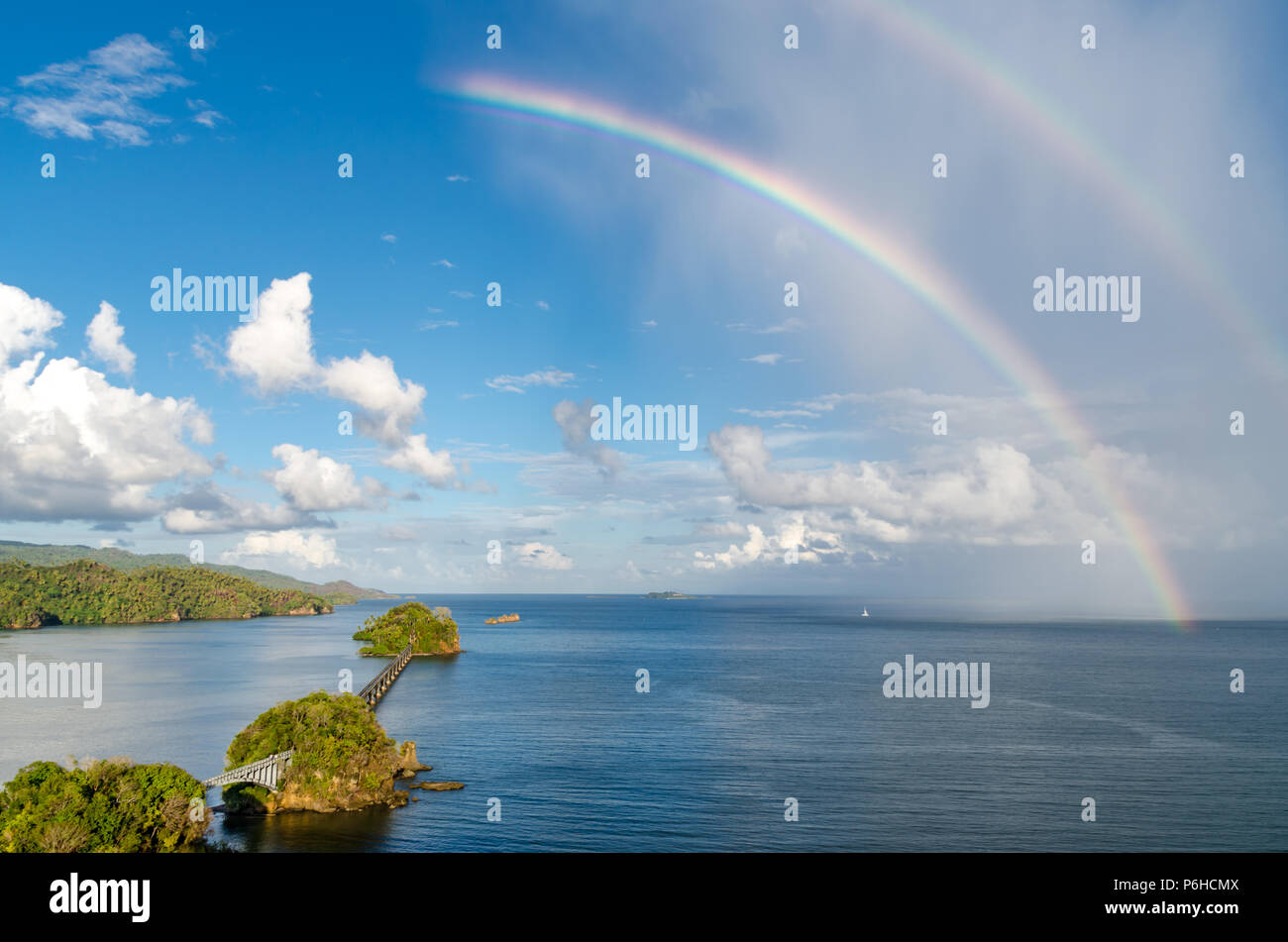 Rainbow oltre oceano in una giornata di sole con il ponte di fronte all'oceano e le nuvole del cielo nella Repubblica Dominicana Foto Stock