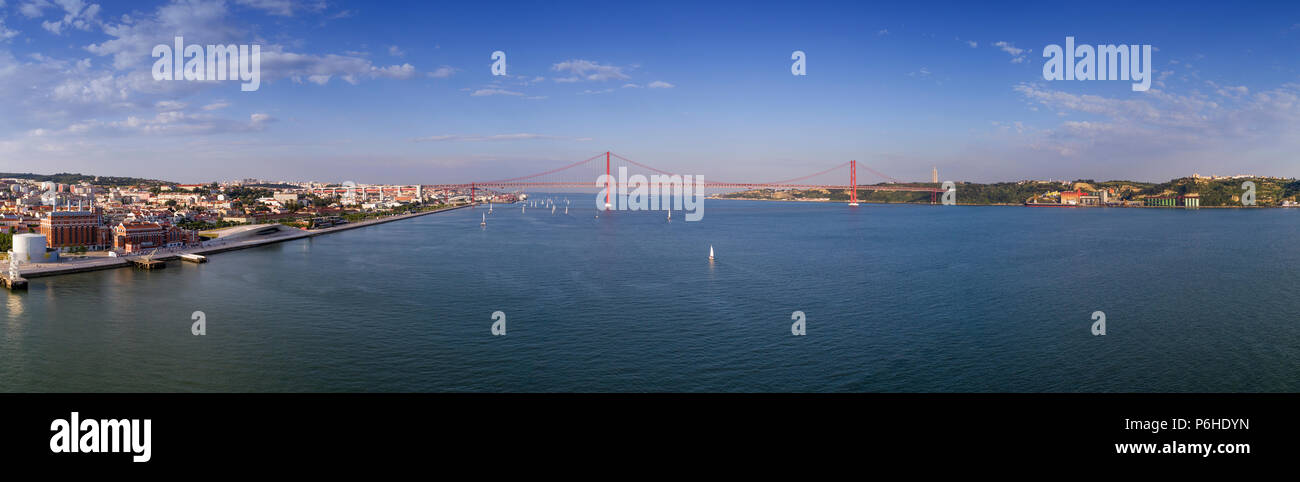 Antenna vista panoramica della città di Lisbona con le barche a vela sul fiume Tago e il 25 di aprile Bridge (Ponte 25 de Abril) sullo sfondo; Conce Foto Stock
