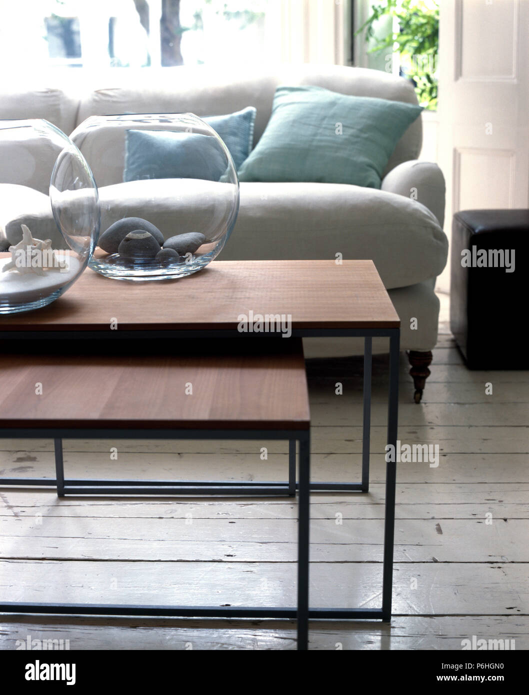 Circolare di ciotole in vetro sul set del moderno metallo e legno impiallacciato con nido di tabelle in un urbano salotto con un divano bianco Foto Stock
