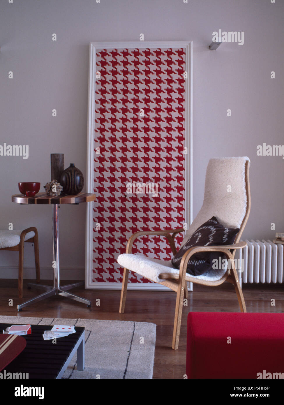 Piccolo piedistallo circolare tavolo e grandi rosso+white houndstooth picture in soggiorno con legno-incorniciato sedia Foto Stock