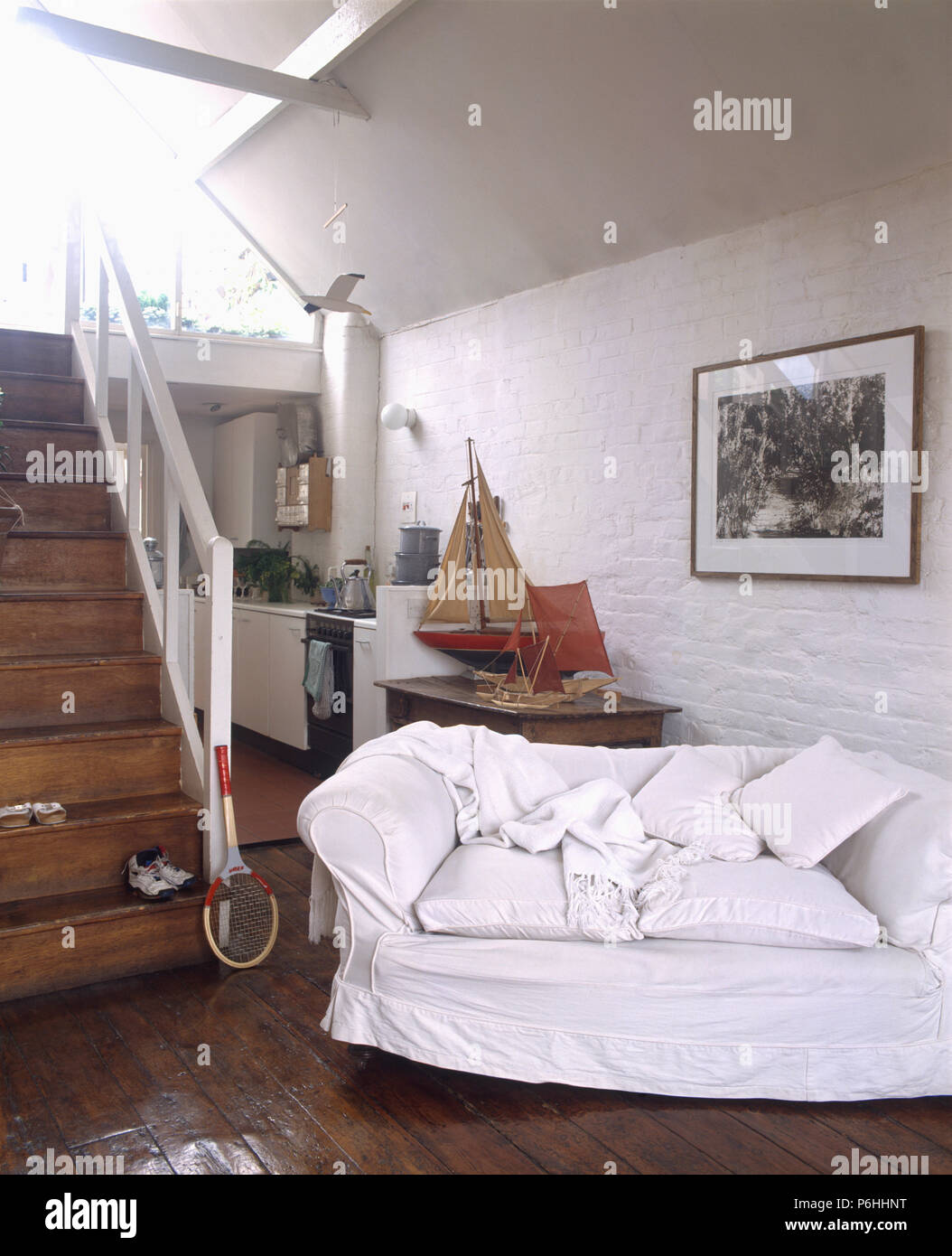 Bianco-allentato il coperchio sul divano in open-plan cottage di un soggiorno e di una cucina con pavimenti in parquet scuro Foto Stock
