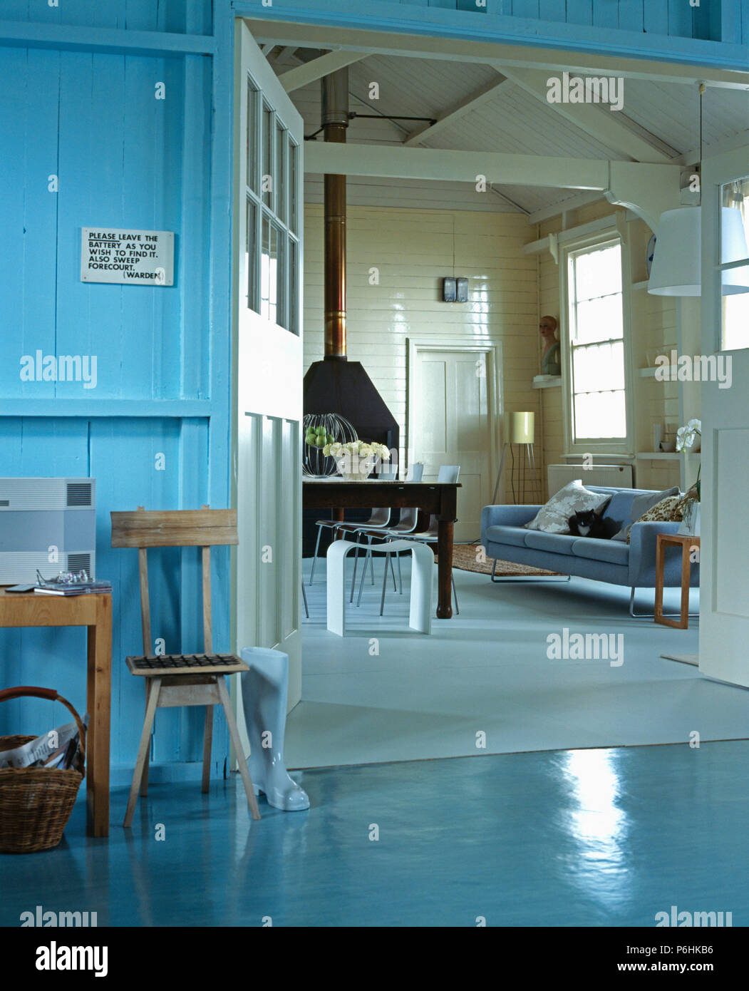 Blu pavimento vinilico nella hall con vista del soggiorno con divano blu in cottage di legno ith con travi a soffitto apex Foto Stock