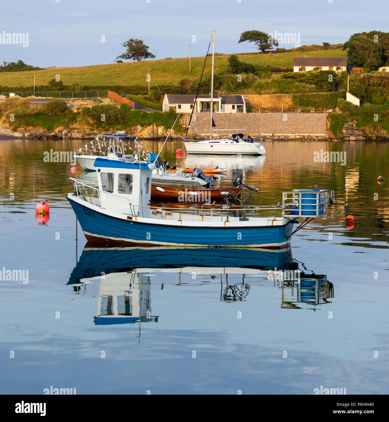 Tramonto sul piatto di calme acque del porto castletownshend, Irlanda, con una miscela di barche al di ancoraggio Foto Stock