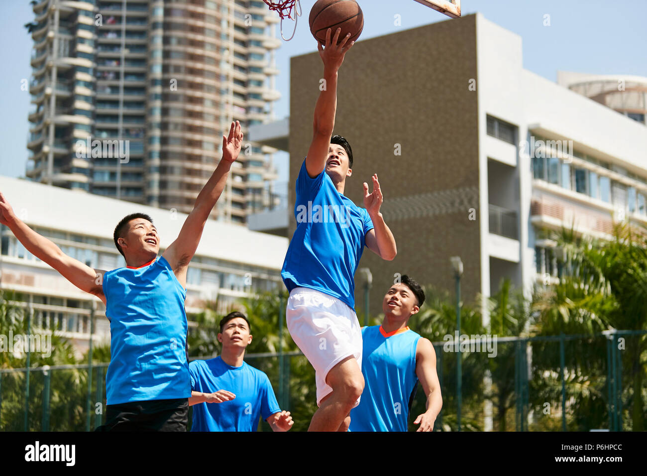 Giovani asiatici maschio adulto giocatore giocare la pallacanestro su un urbano corte esterna. Foto Stock
