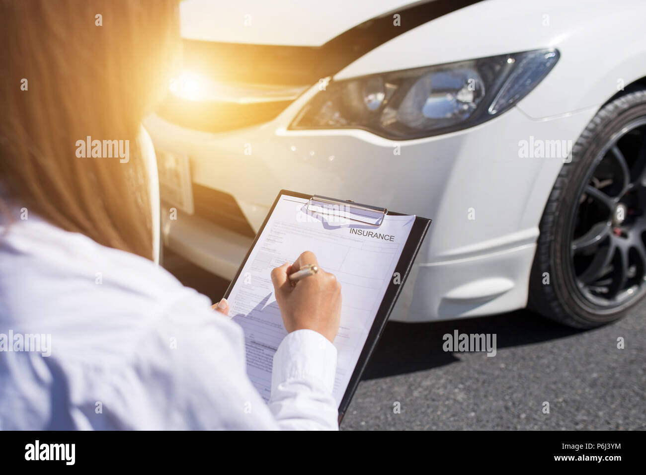 Vista laterale della scrittura sulla clipboard mentre agente di assicurazione auto esame dopo un incidente Foto Stock