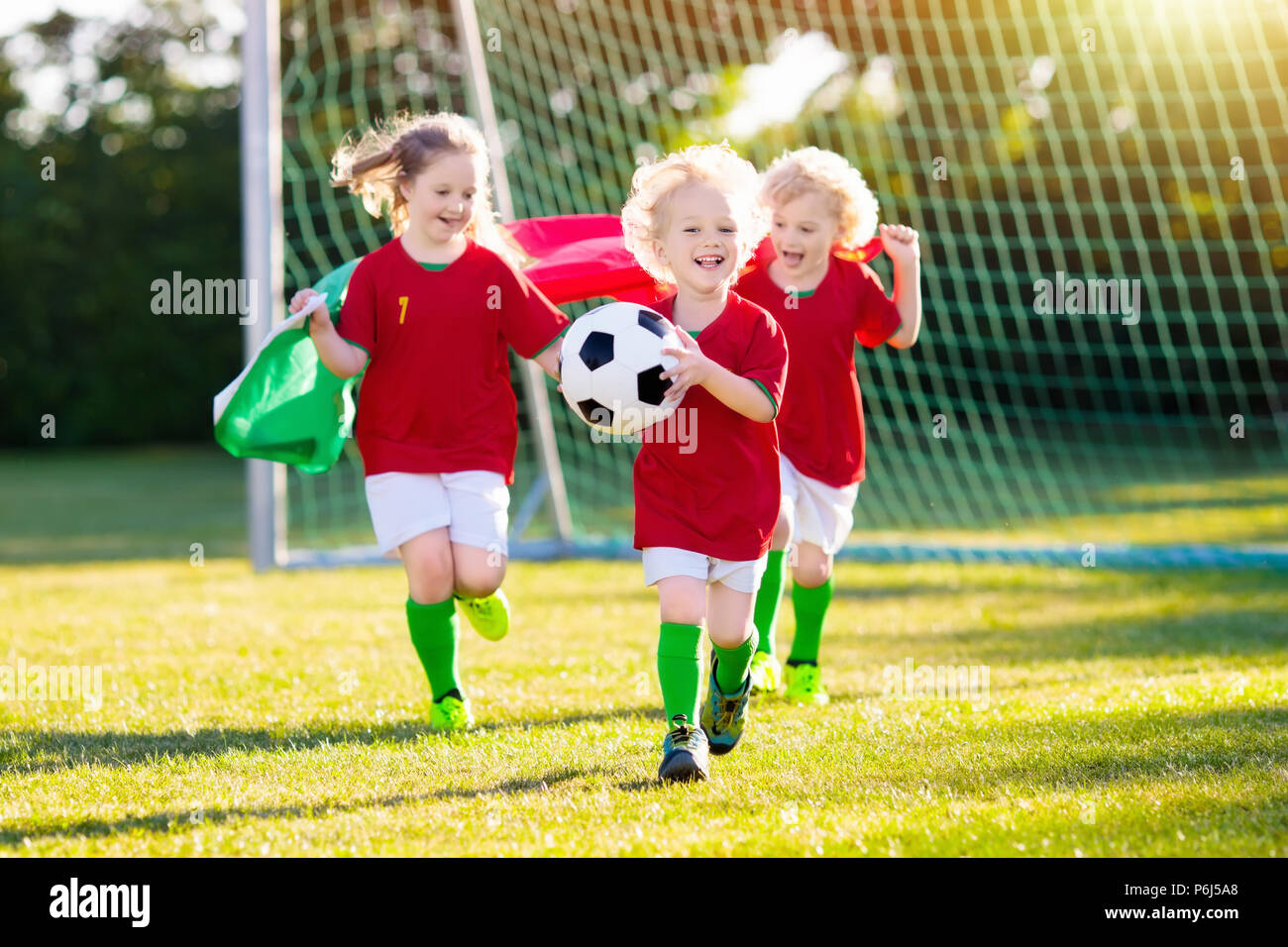 I bambini giocano a calcio sul campo all'aperto. In Portogallo i fan del  team con la bandiera nazionale. Bambini segnare un gol a partita di calcio.  Bambino in portoghese jersey e gancio