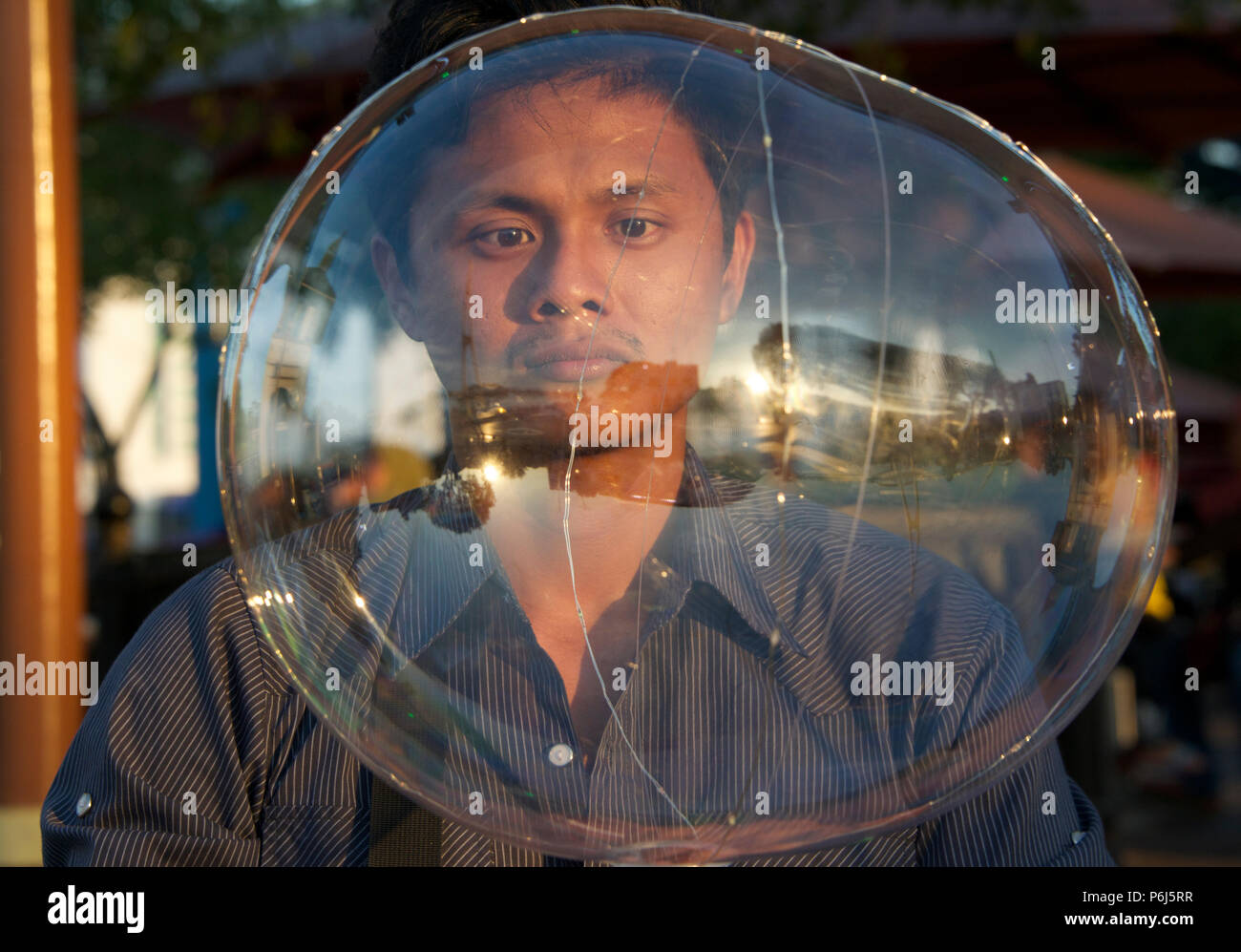 Ritratto di un uomo visto attraverso la bolla di sapone gigante waterfront promenade Kuching Sarawak Malaysia Foto Stock