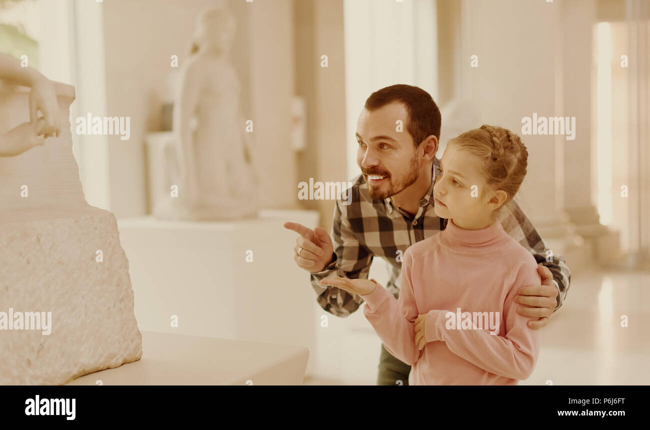 Uomo positivo e piccola ragazza spiegazione antiche statue in museo Foto Stock