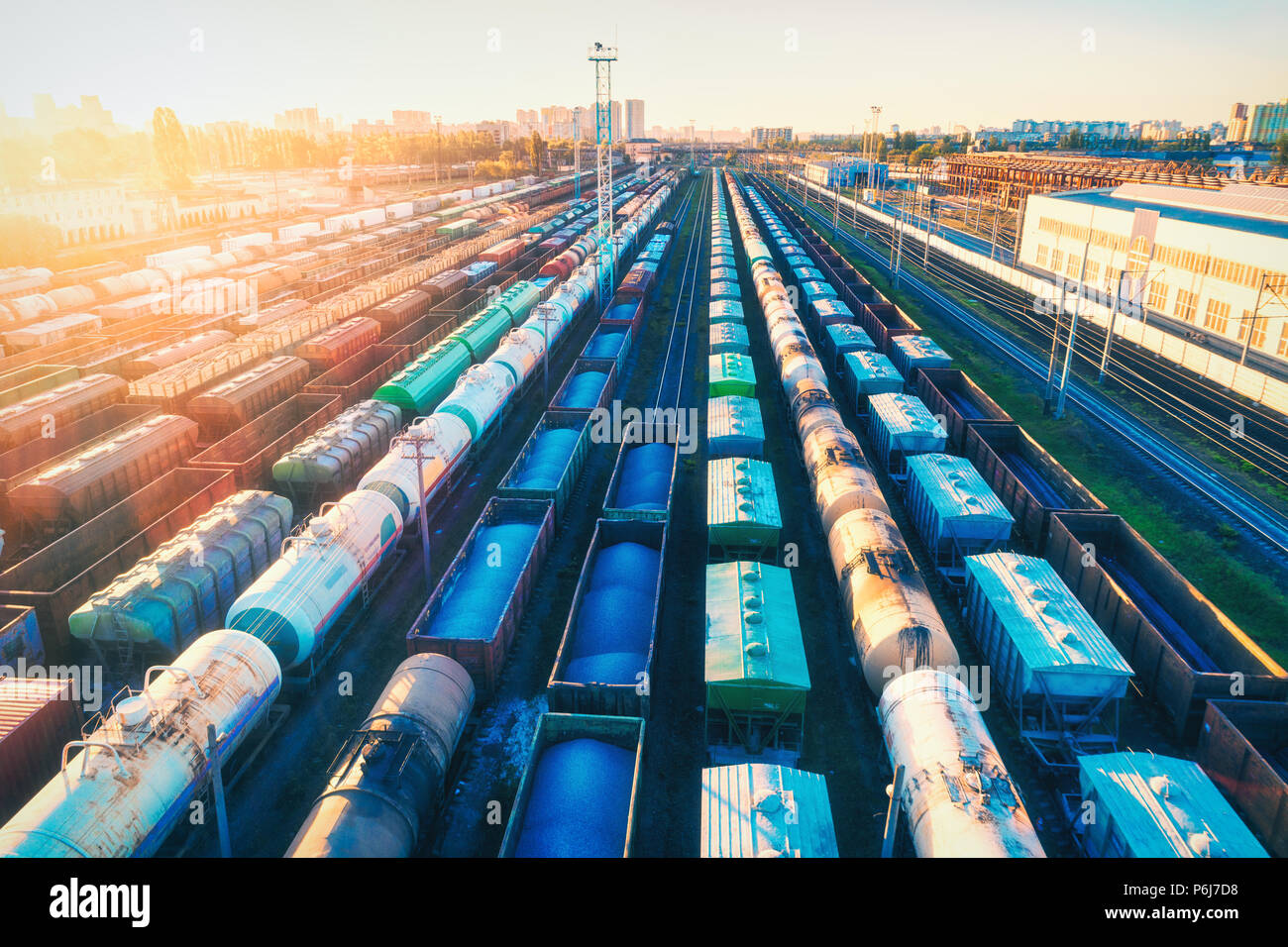 Vista aerea di coloratissimi treni merci al tramonto. Carri merci con merci sulla stazione ferroviaria. Ferrovia. Industria pesante. Paesaggio industriale con rotaia Foto Stock