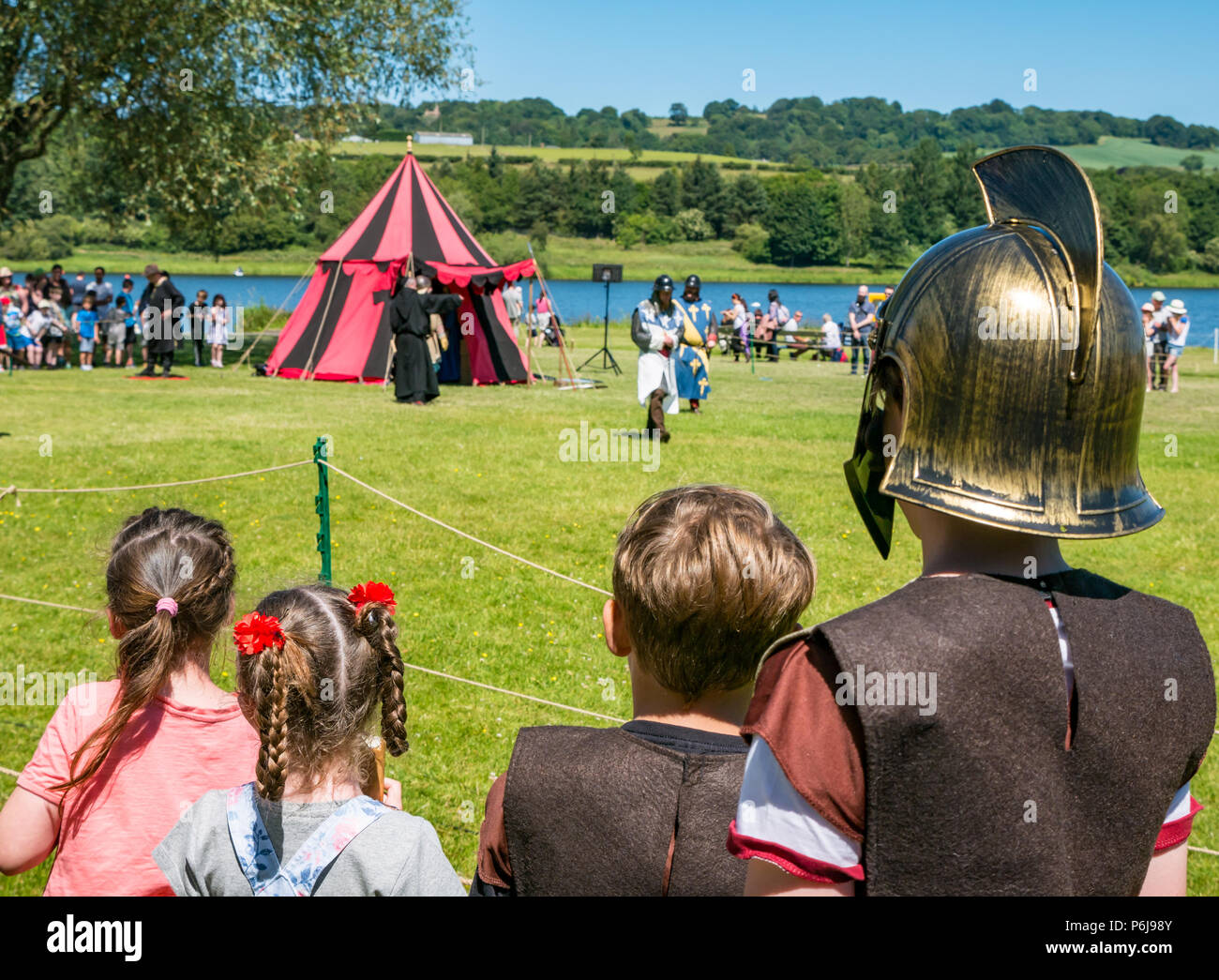 Giostre e Fiera medievale a Linlithgow Palace, Linlithgow, Scotland, Regno Unito, 30 giugno 2018. Ambiente storico la Scozia ha dato dei calci a fuori il loro programma di intrattenimento estivo con un favoloso display della giostra medievale nel parco del castello storico. Il divertimento in famiglia al giorno inclusa una storia viva camp e giochi medievali. Il centro storico si intraversa società eseguire e presentare una viva borgo medievale. Due ragazzi vestito di soldati romani costumi e due bambine guarda una performance Foto Stock