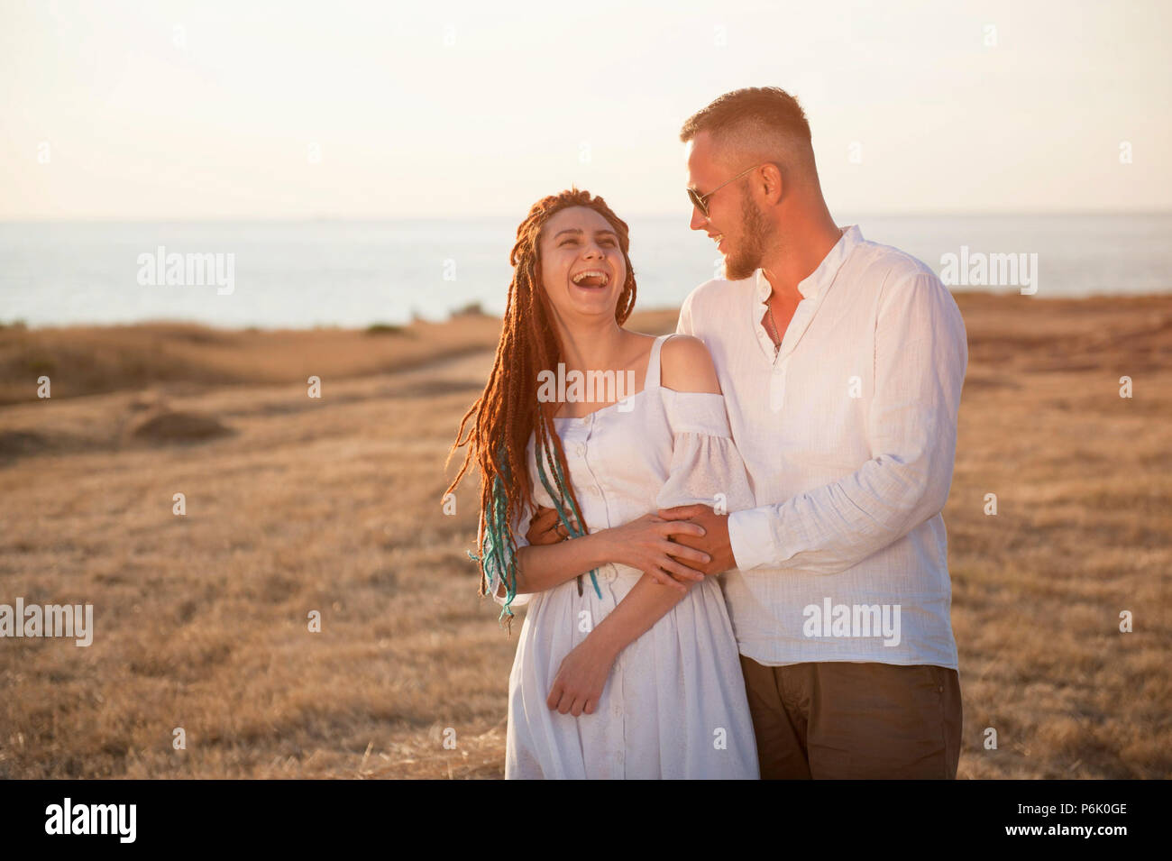 Carino il ragazzo in occhiali da sole abbracciando la fidanzata con dreadlocks sulla riva del mare in estate Foto Stock