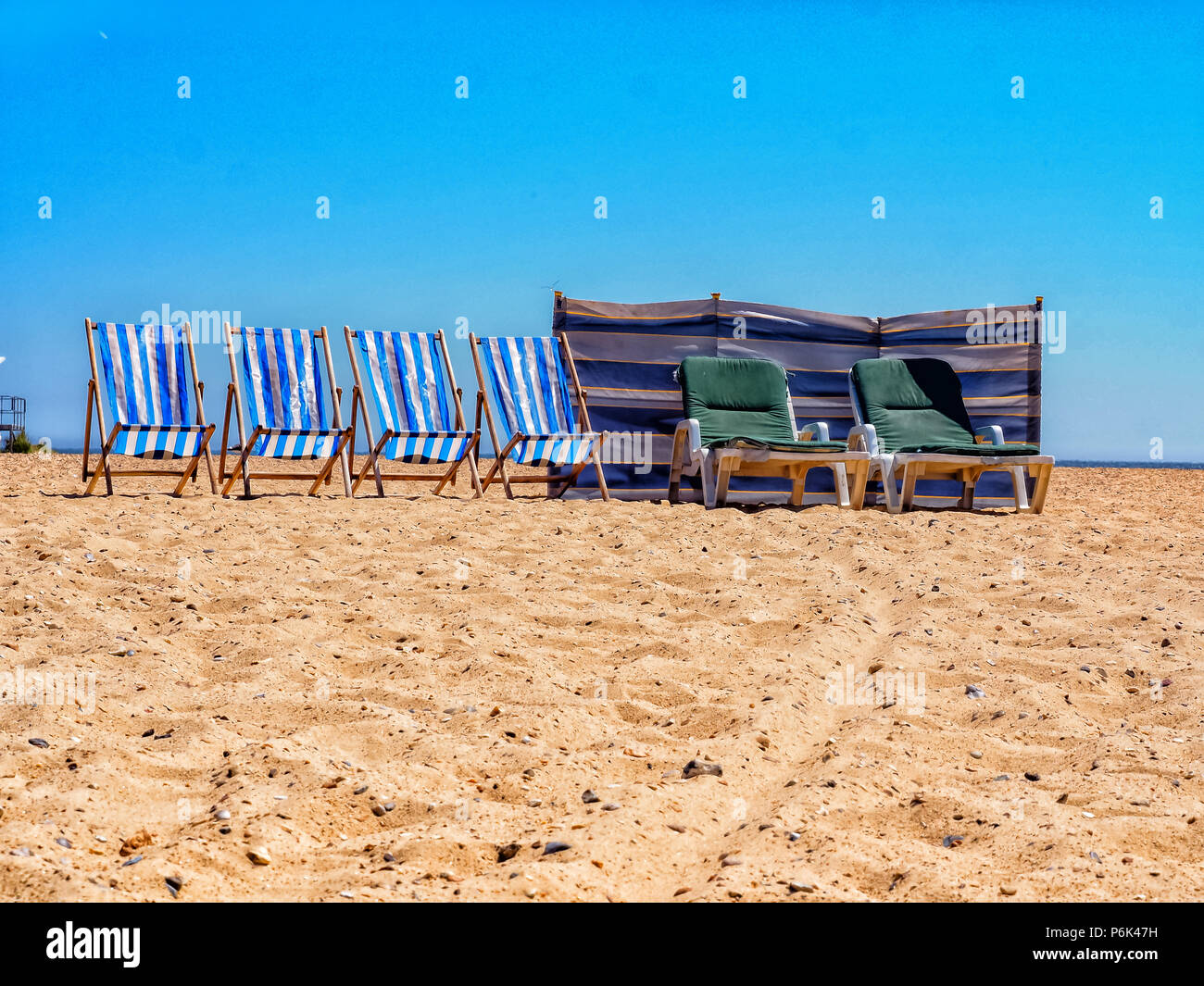 Una fila di sedie a sdraio e lettini per prendere il sole su di una spiaggia di sabbia Foto Stock