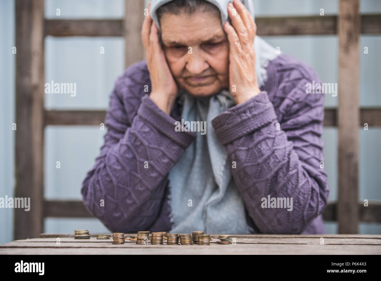 Soldi, monete, nonna titolare di pensione o di rendita e il concetto di minimo di sussistenza - vecchia donna triste guardando le monete Foto Stock