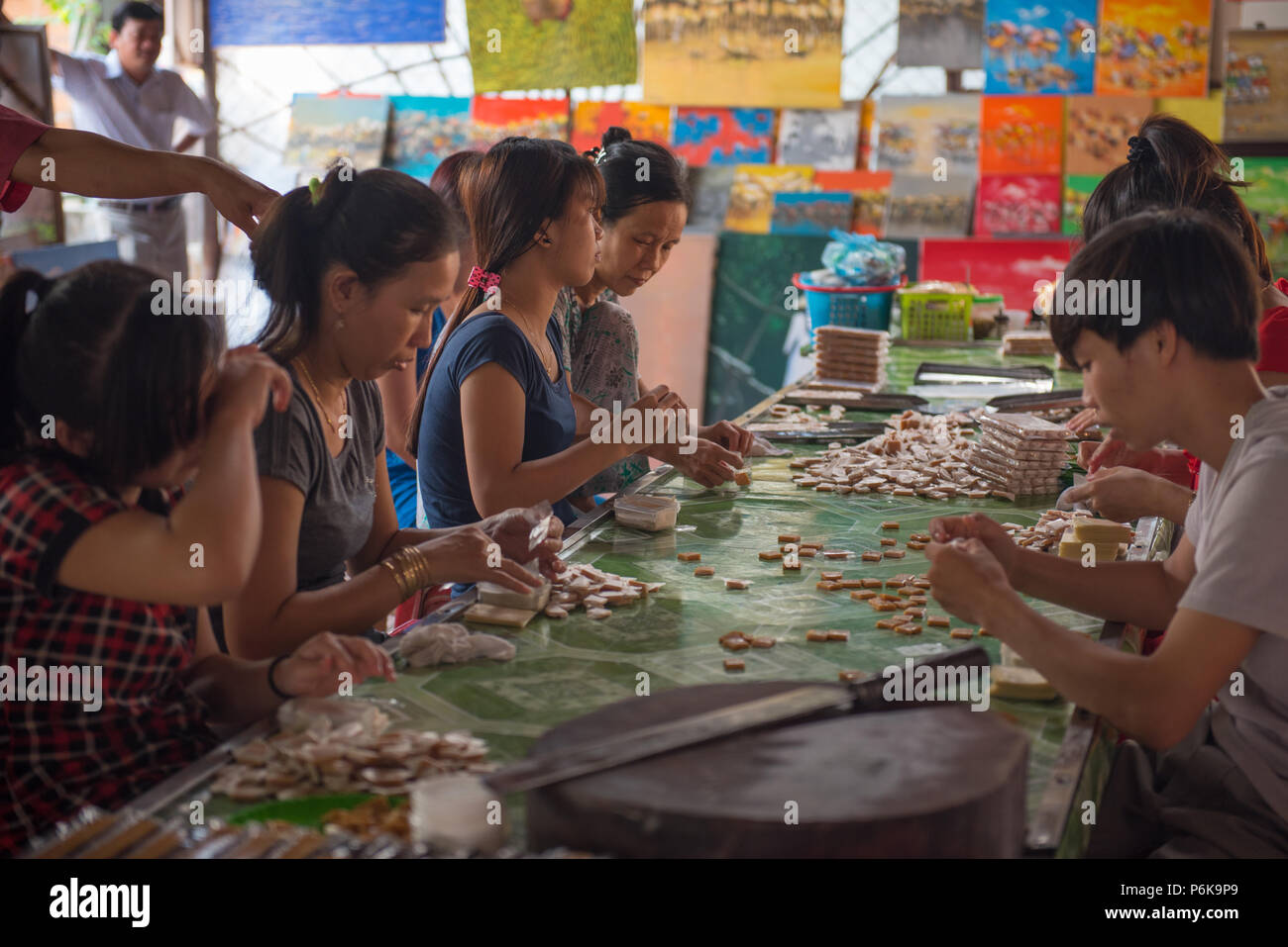 Il fiume Mekong, Vietnam -- 20 marzo 2016 lavoratori in una piccola casa fabbrica di base lungo il fiume Mekong rendendo la caramella. Foto Stock