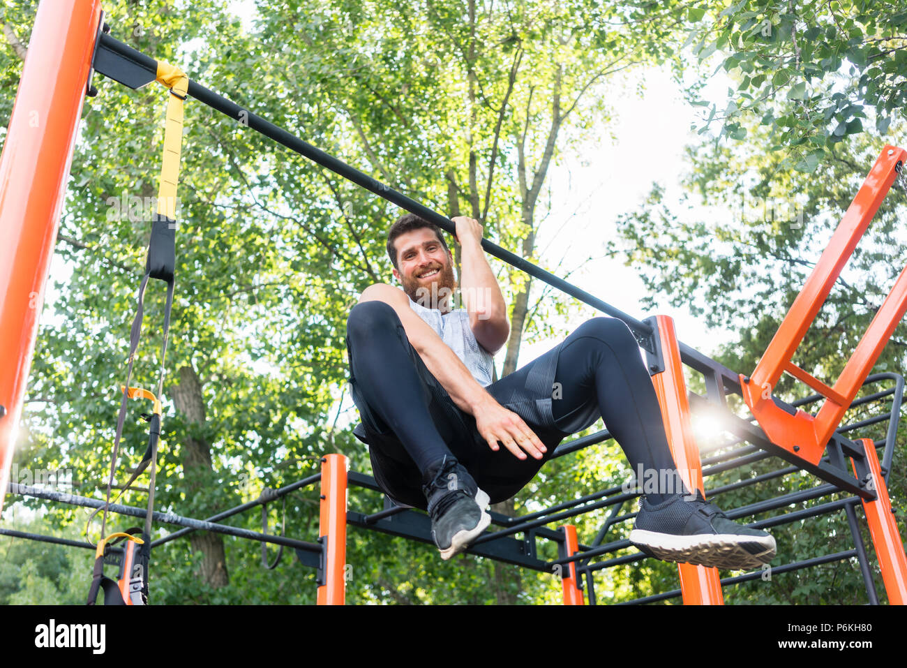 Potente giovane uomo che fa un braccio-pull-up mentre è appesa su una barra Foto Stock