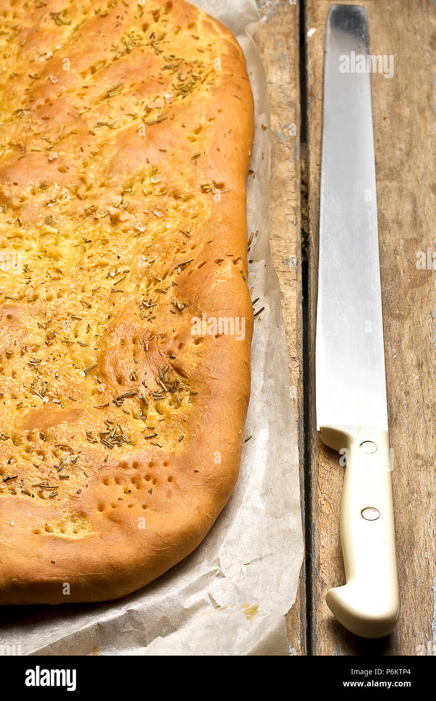 Vista superiore del pane foccacia con rosmarino e il coltello in legno tavolo rustico Foto Stock