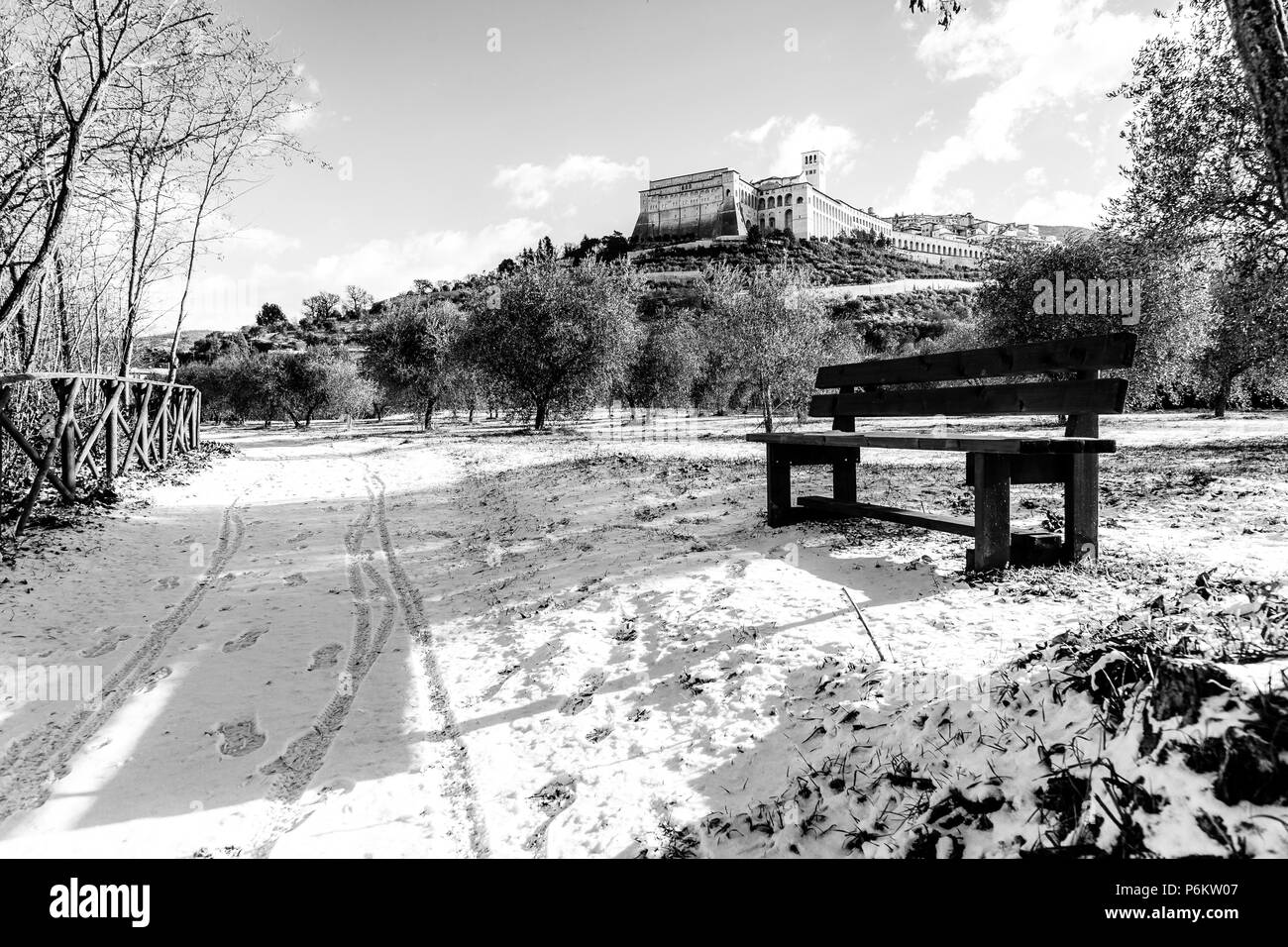 Vista della città di Assisi (Umbria) in inverno, con un paese di strade coperte da neve e cielo con nuvole bianche Foto Stock