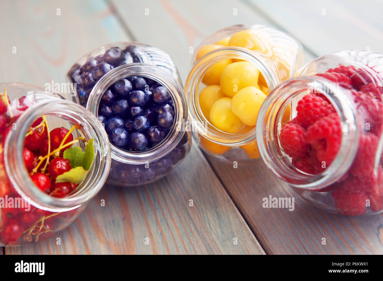 Organico sani frutti nel vasetto di vetro su uno sfondo di legno. Ciliegia, Berry, mirtillo, lampone Foto Stock