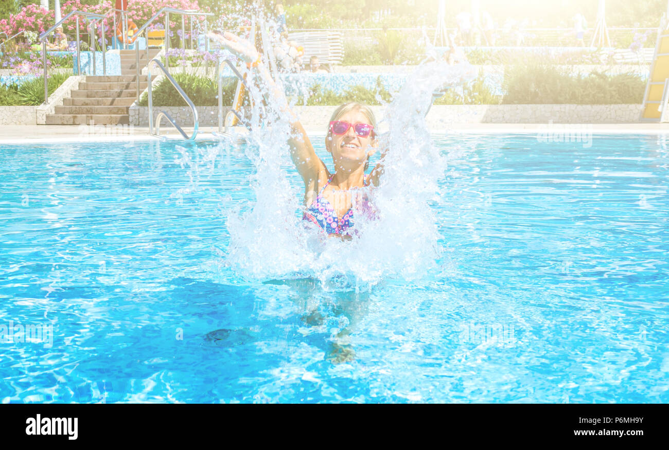 Giovane donna bionda con bikini colorati godendo di giornata di sole presso la piscina Foto Stock