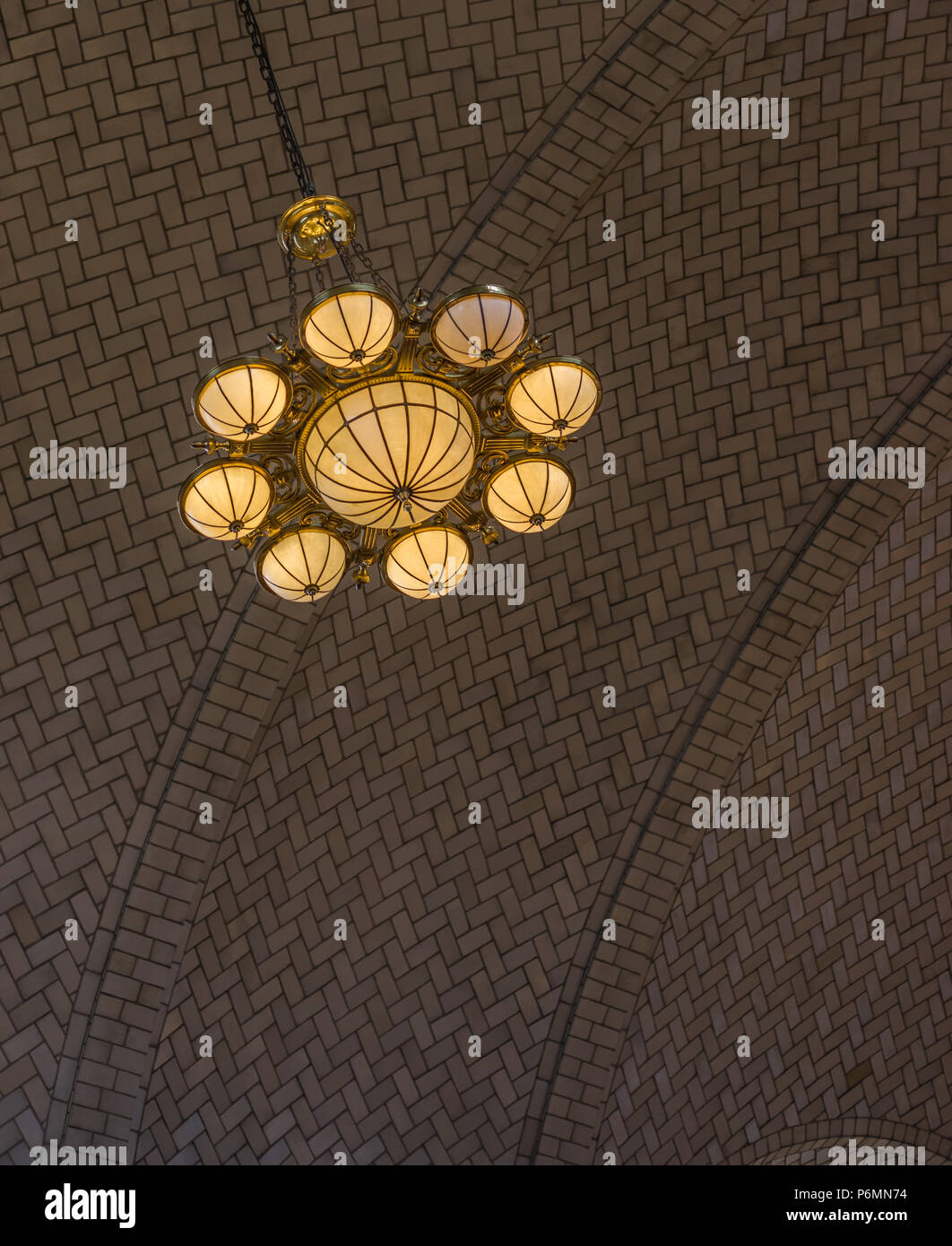 Bellissima lampada ornati pende da una stile herrinbone acrhed soffitto nell'area ricevimento su Ellis Island, off Manhattan, New York City ornato lampada h Foto Stock