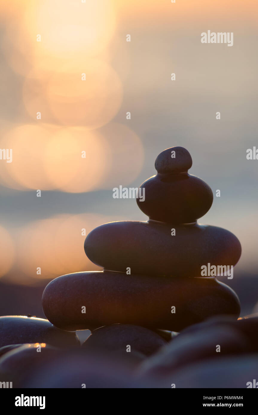 Piramide piegata Zen pietre ghiaia sul mare spiaggia al tramonto Foto Stock