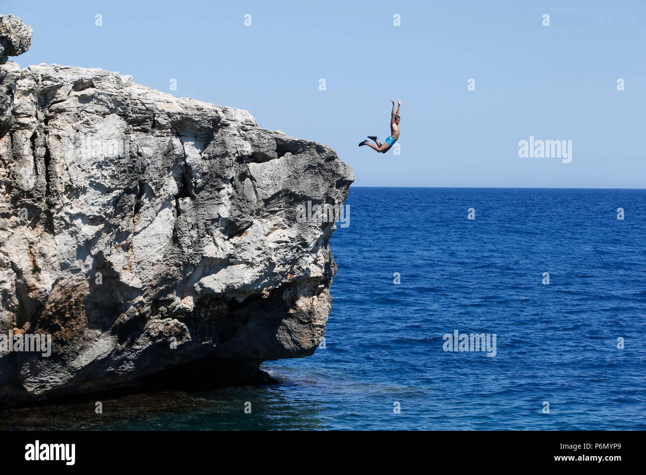 11-anno-vecchio ragazzo che salta da un dirupo nel mare del Salento, Italia. Foto Stock