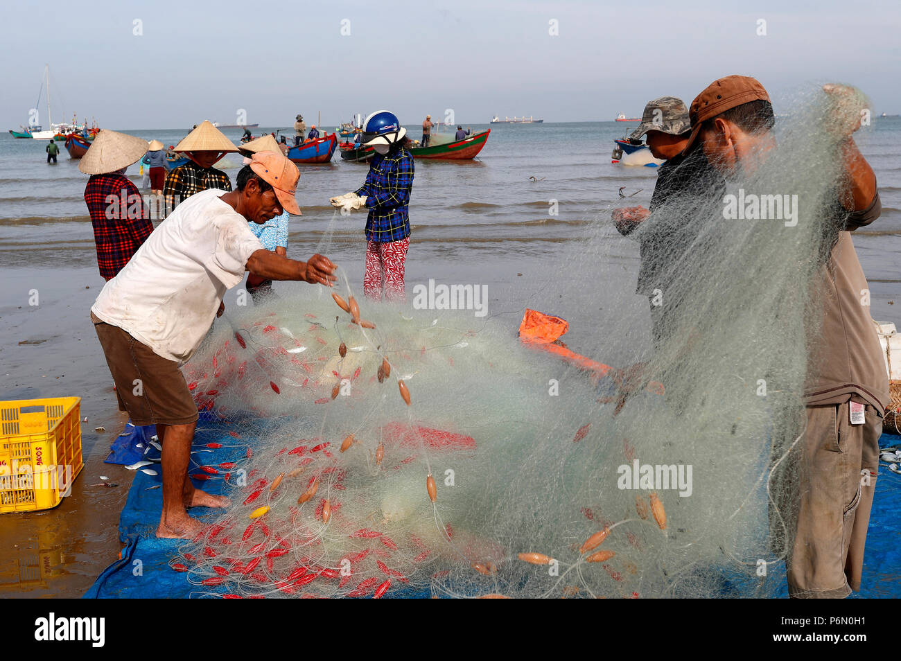 I pescatori la riparazione di reti da pesca a Tam Duong beach. Vung Tau. Il Vietnam. Foto Stock