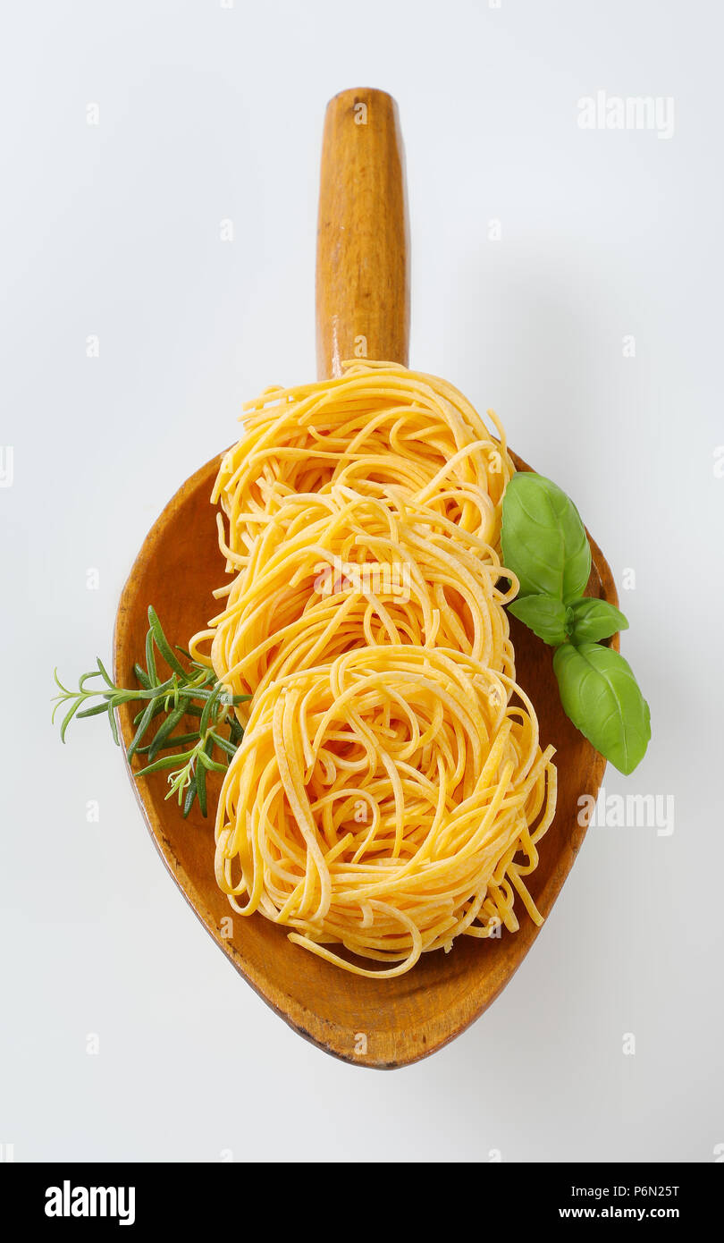 Fasci di spaghetti e le erbe in un cucchiaio di legno Foto Stock