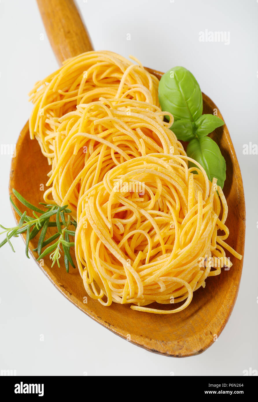 Fasci di spaghetti e le erbe in un cucchiaio di legno Foto Stock