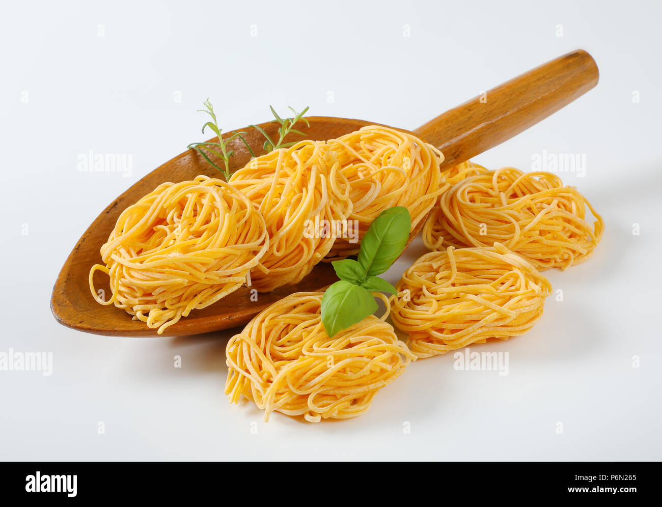 Fasci di spaghetti e le erbe in un cucchiaio di legno Foto Stock
