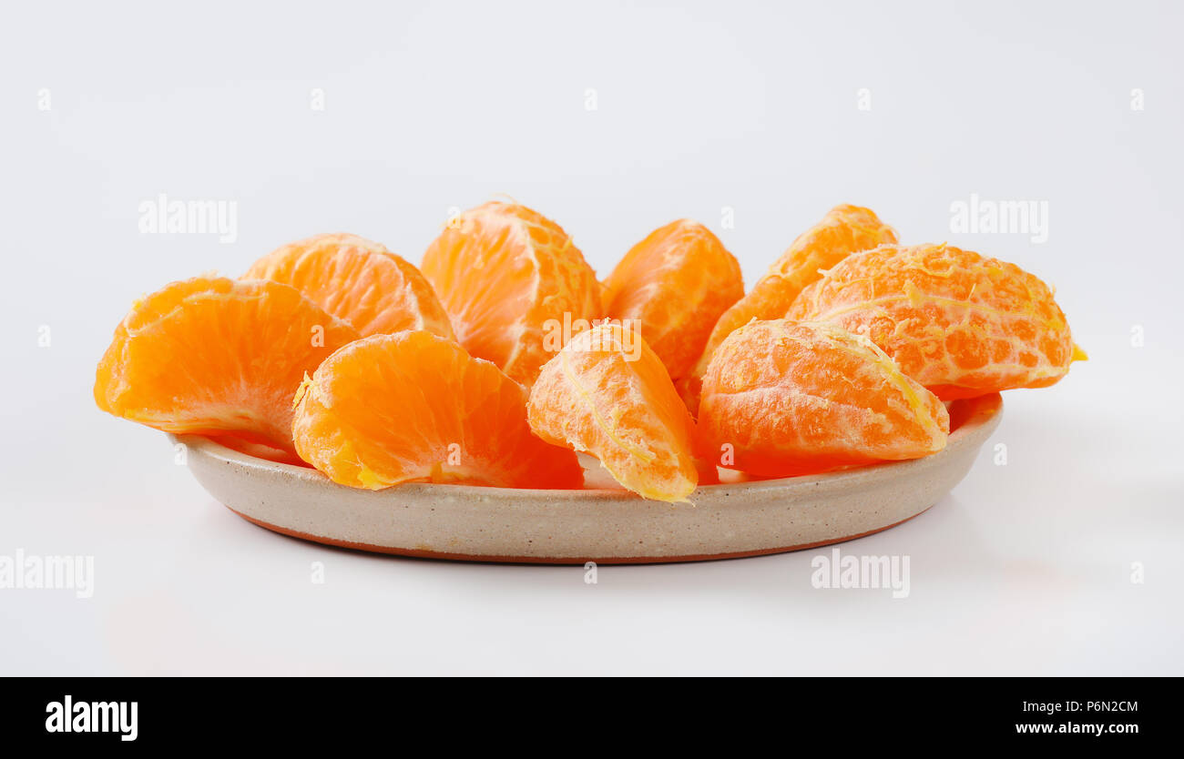 Piastra di fresco mandarino le fette su sfondo bianco Foto Stock
