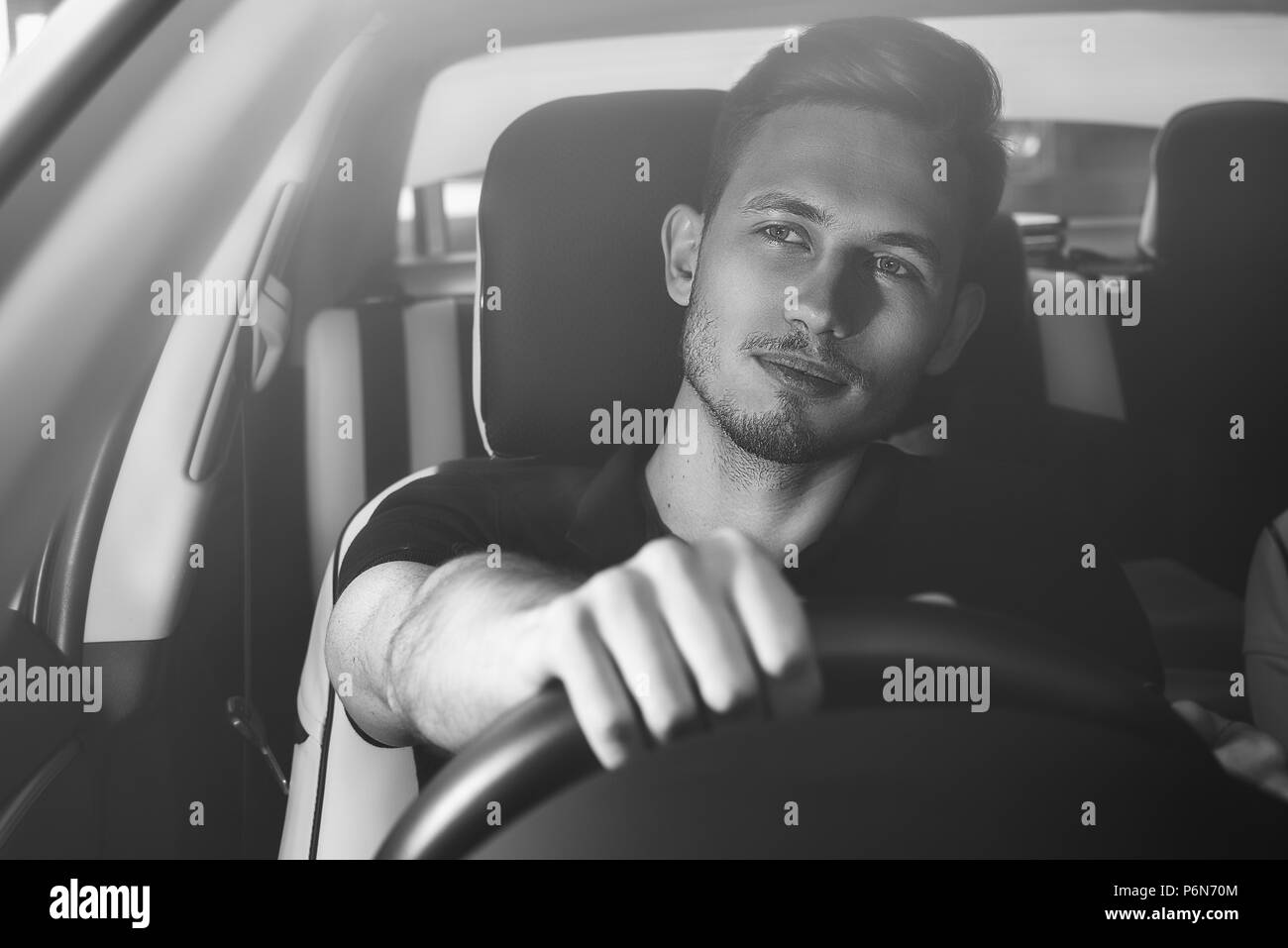 Bel uomo seduto in un auto e trattenendo il volante. Foto Stock