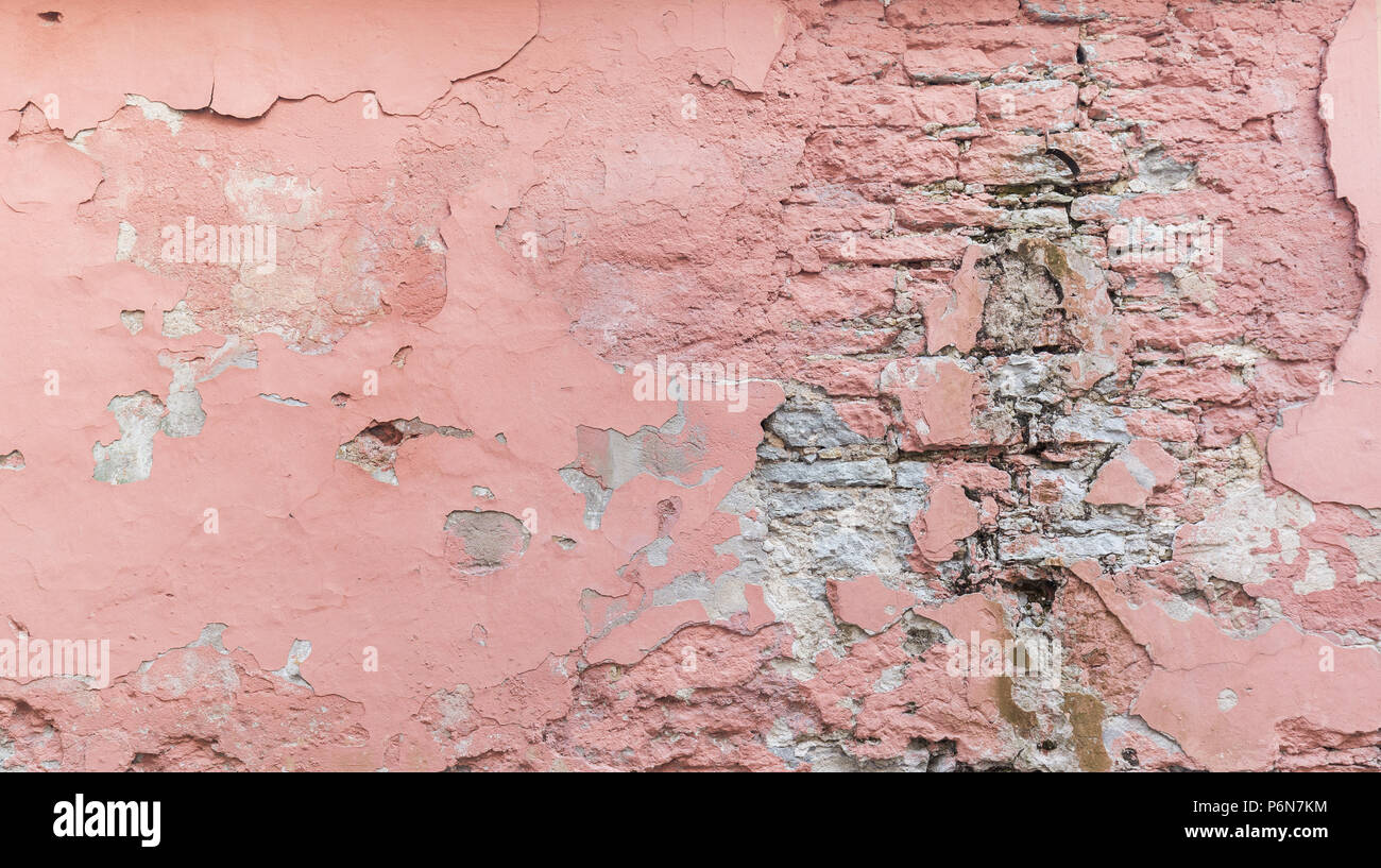 Telaio completo sullo sfondo di un weathered, danneggiato e muro intonacato dipinta in rosa. Il gesso è parzialmente distaccata rivelando vecchi mattoni. Foto Stock