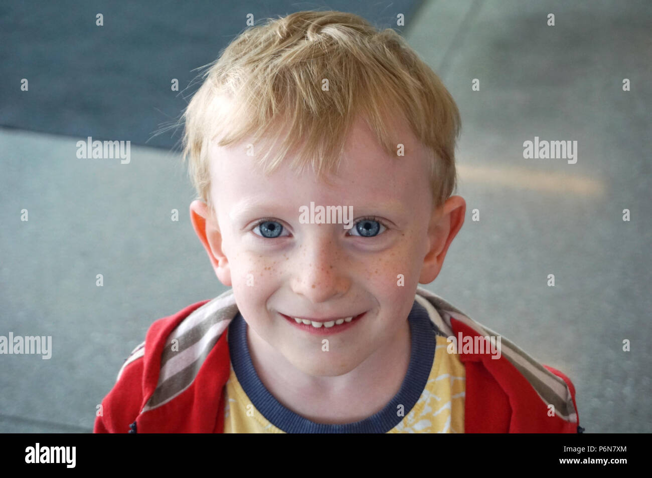 Grazioso e piccolo felice ragazzo con bellissimi occhi azzurri e capelli biondi, bambino close-up verticale, il concetto di infanzia di felicità e di innocenza Foto Stock