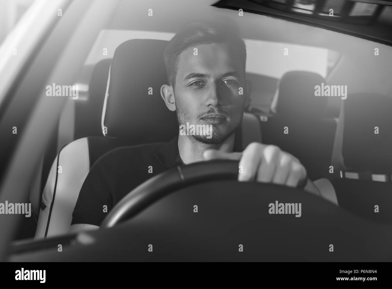 Bel uomo seduto in un auto e trattenendo il volante. Foto Stock