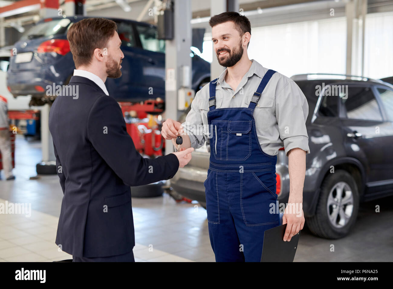 Meccanico di automobili che dà le chiavi a imprenditore Foto Stock