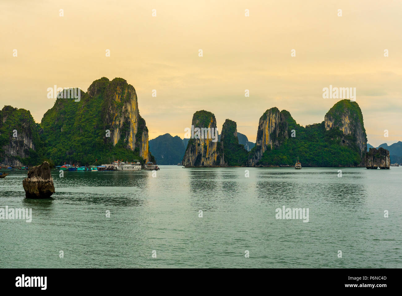 Un villaggio galleggiante si trova alla base di una formazione rocciosa nella baia di Halong, Vietnam Foto Stock